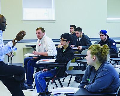 Olu Onafowora teaches in front of a classroom of students.